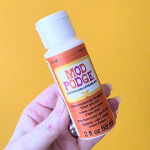 Flesje Mod Podge Gloss 59 ml als fixatie voor pastel tiles Mod Podge Gloss van Plaid, 2 fl oz oftewel 59 ml Mod Podge Gloss lijm sealer en lak op waterbasis in de hand